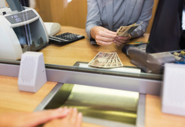 people, withdrawal, saving and finance concept - clerk counting cash money for customer at bank office or currency exchanger